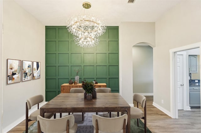 19113 Golden Cacoon Pl, Lutz, FL 33558 - dining room with a decorative wall, arched walkways, a chandelier, and light wood-style floors