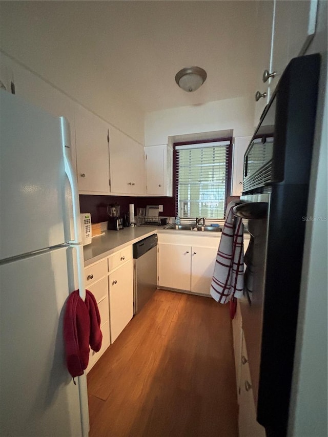 223 Windsor St Unit 6, Lakeland, FL 33803 - kitchen with freestanding refrigerator, stainless steel dishwasher, wood finished floors, white cabinetry, and light countertops
