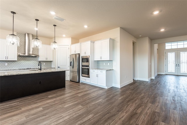 8749 Drummer Plank Dr, Wesley Chapel, FL 33545 - kitchen featuring wall chimney range hood, appliances with stainless steel finishes, decorative backsplash, dark wood-style flooring, and white cabinetry