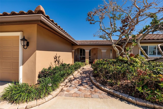 208 Bath Club Blvd N, North Redington Beach, FL 33708 - view of exterior entry featuring stucco siding, a tiled roof, and an attached garage