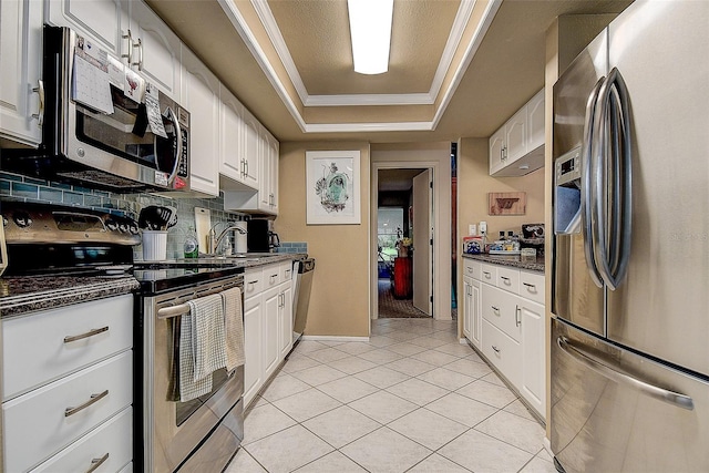 140 Dale Pl, Oldsmar, FL 34677 - kitchen featuring stainless steel appliances, a raised ceiling, white cabinetry, light tile patterned floors, and tasteful backsplash