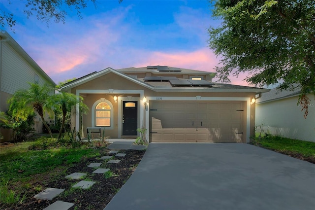 11130 Summer Star Dr, Riverview, FL 33579 - view of front of home with an attached garage, driveway, roof mounted solar panels, stucco siding, and a porch