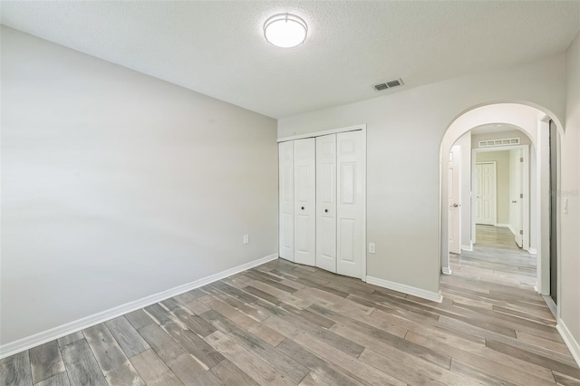 11130 Summer Star Dr, Riverview, FL 33579 - unfurnished bedroom featuring light wood-type flooring, arched walkways, a closet, and a textured ceiling