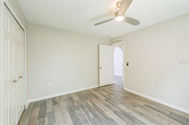 11130 Summer Star Dr, Riverview, FL 33579 - unfurnished bedroom with light wood-style flooring, a closet, ceiling fan, and arched walkways