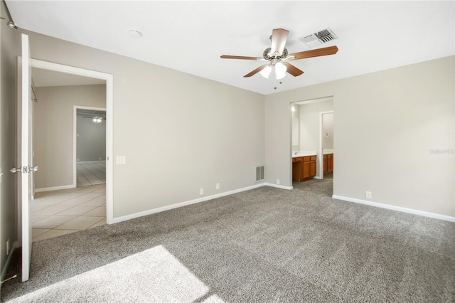 9807 Stephenson Dr, New Port Richey, FL 34655 - unfurnished bedroom with light colored carpet, ensuite bath, light tile patterned flooring, and a ceiling fan