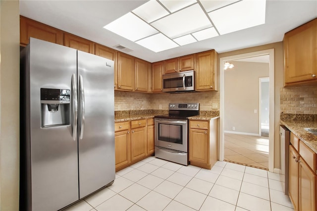 9807 Stephenson Dr, New Port Richey, FL 34655 - kitchen featuring stainless steel appliances, decorative backsplash, light tile patterned floors, stone countertops, and brown cabinetry