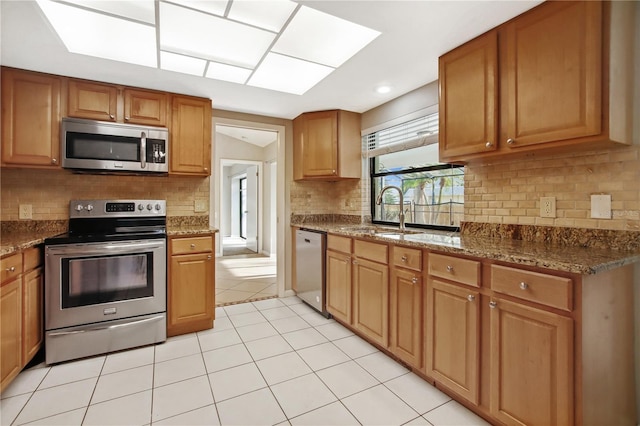 9807 Stephenson Dr, New Port Richey, FL 34655 - kitchen with appliances with stainless steel finishes, decorative backsplash, light tile patterned floors, brown cabinetry, and dark stone countertops