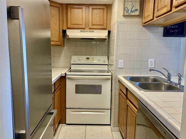 4712 Marine Pkwy Unit 203, New Port Richey, FL 34652 - kitchen with appliances with stainless steel finishes, under cabinet range hood, tile countertops, and brown cabinetry
