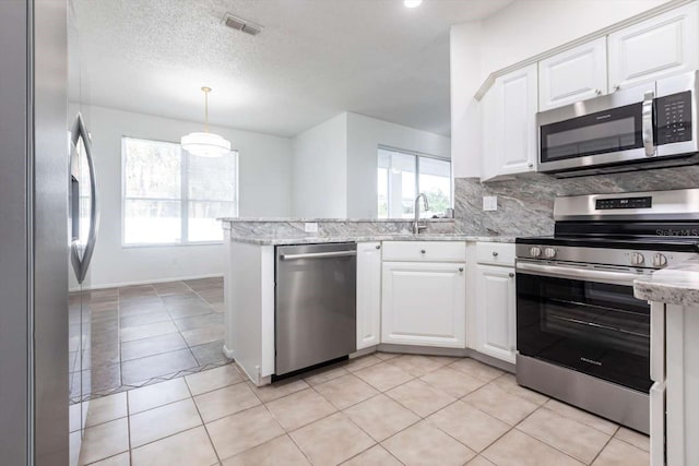 5017 46th St W, Bradenton, FL 34210 - kitchen with stainless steel appliances, white cabinetry, decorative backsplash, a peninsula, and a textured ceiling