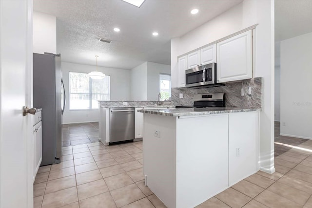5017 46th St W, Bradenton, FL 34210 - kitchen featuring stainless steel appliances, a peninsula, white cabinetry, tasteful backsplash, and light tile patterned floors