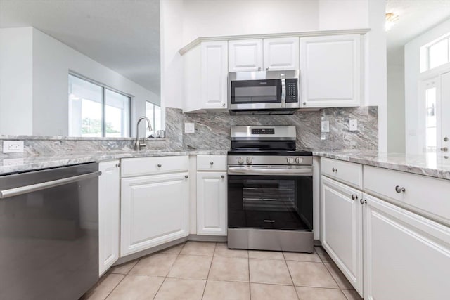 5017 46th St W, Bradenton, FL 34210 - kitchen featuring stainless steel appliances, backsplash, light tile patterned floors, and white cabinets