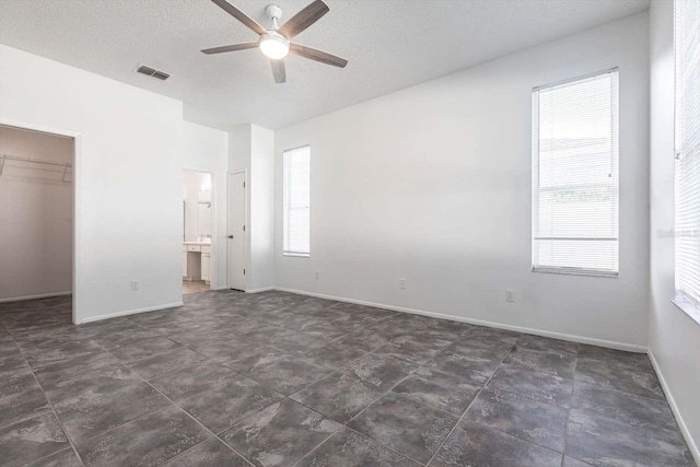 5017 46th St W, Bradenton, FL 34210 - unfurnished bedroom with a walk in closet, a closet, a textured ceiling, ensuite bathroom, and a ceiling fan