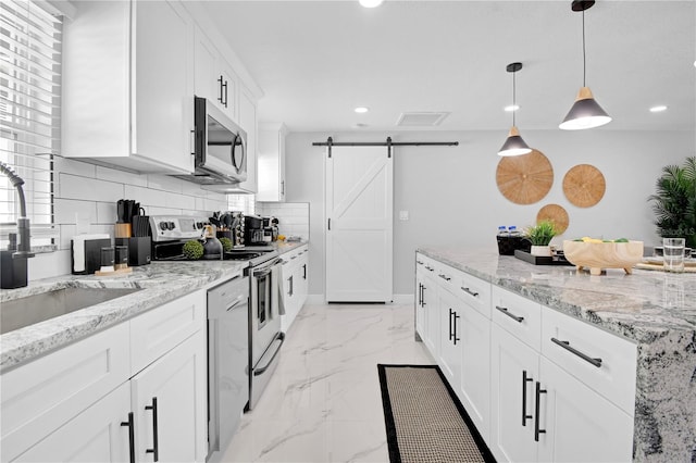 8010 W Hiawatha St, Tampa, FL 33615 - kitchen with stainless steel appliances, a barn door, recessed lighting, light marble finish flooring, and backsplash