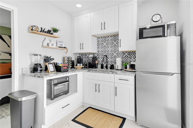 8010 W Hiawatha St, Tampa, FL 33615 - kitchen with freestanding refrigerator, stainless steel microwave, open shelves, white cabinets, and decorative backsplash
