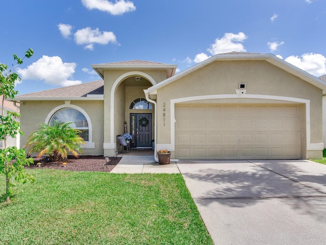 24811 Gun Smoke Dr, Land O Lakes, FL 34639 - mediterranean / spanish-style house featuring an attached garage, stucco siding, concrete driveway, a front yard, and a shingled roof