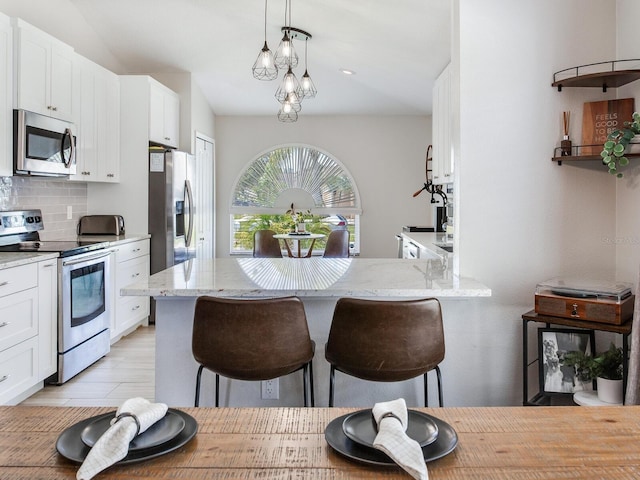 24811 Gun Smoke Dr, Land O Lakes, FL 34639 - kitchen with appliances with stainless steel finishes, white cabinets, backsplash, a kitchen breakfast bar, and vaulted ceiling