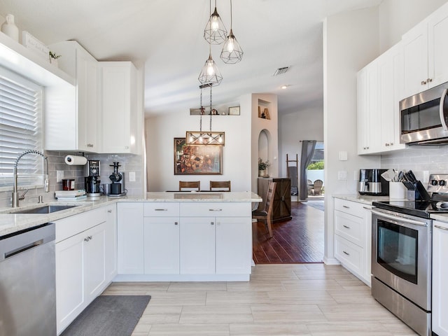 24811 Gun Smoke Dr, Land O Lakes, FL 34639 - kitchen with appliances with stainless steel finishes, decorative backsplash, white cabinets, light stone countertops, and hanging light fixtures
