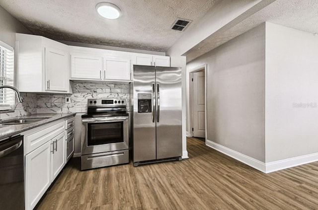 10215 N 23rd St, Tampa, FL 33612 - kitchen featuring appliances with stainless steel finishes, a textured ceiling, wood finished floors, and white cabinetry