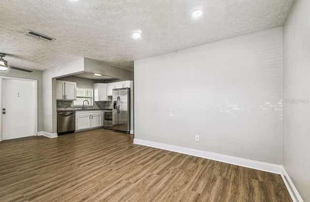10215 N 23rd St, Tampa, FL 33612 - kitchen with appliances with stainless steel finishes, dark wood-style flooring, a textured ceiling, white cabinetry, and dark countertops