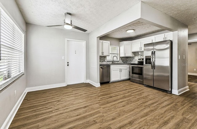 10215 N 23rd St, Tampa, FL 33612 - kitchen with stainless steel appliances, a textured ceiling, dark countertops, white cabinetry, and dark wood-style floors