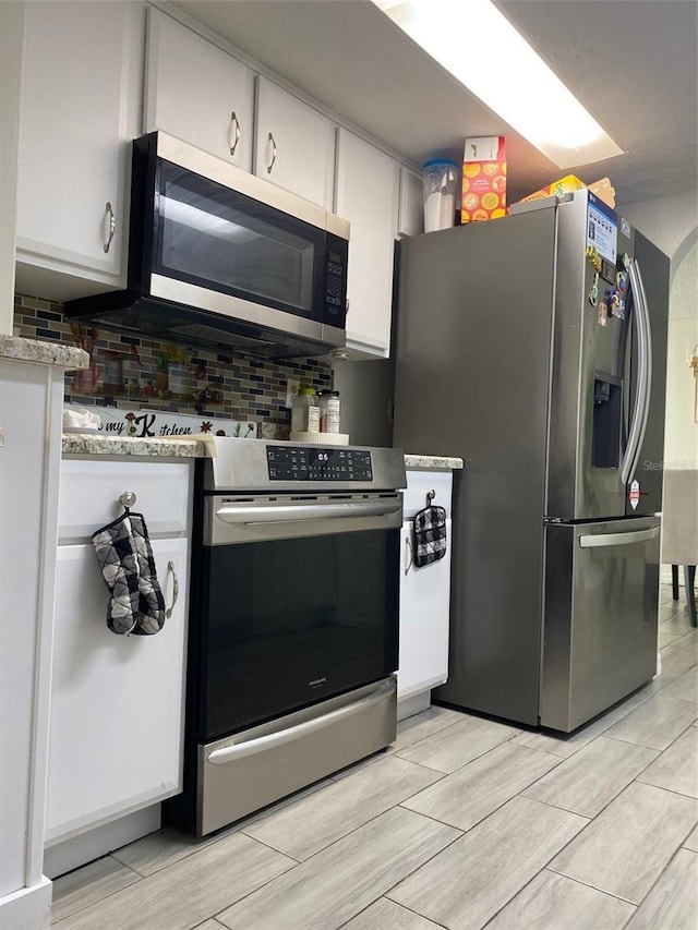 4219 Gray Squirrel Ln, New Port Richey, FL 34653 - kitchen with stainless steel appliances, tasteful backsplash, white cabinets, wood finish floors, and light countertops