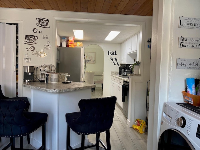 4219 Gray Squirrel Ln, New Port Richey, FL 34653 - kitchen featuring freestanding refrigerator, wooden ceiling, a breakfast bar area, white cabinetry, and a peninsula