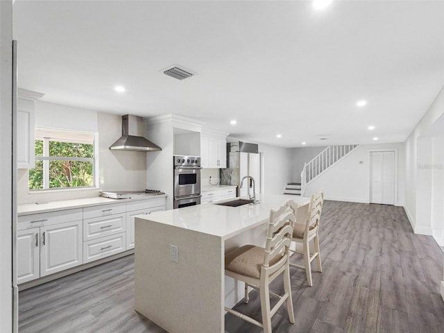 2440S Wallace Rd, Bartow, FL 33830 - kitchen with wall chimney exhaust hood, stainless steel double oven, a kitchen breakfast bar, light wood finished floors, and recessed lighting