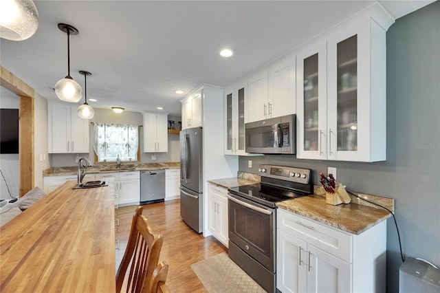 2914 Forest Cir, Seffner, FL 33584 - kitchen featuring stainless steel appliances, butcher block countertops, white cabinets, light wood-style flooring, and pendant lighting
