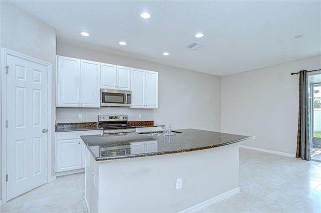 7077 Woodchase Glen Dr, Riverview, FL 33578 - kitchen with appliances with stainless steel finishes, dark stone countertops, white cabinets, a kitchen island with sink, and recessed lighting