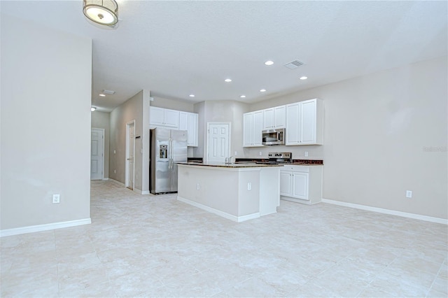 7077 Woodchase Glen Dr, Riverview, FL 33578 - kitchen featuring appliances with stainless steel finishes, dark countertops, white cabinets, a center island with sink, and recessed lighting