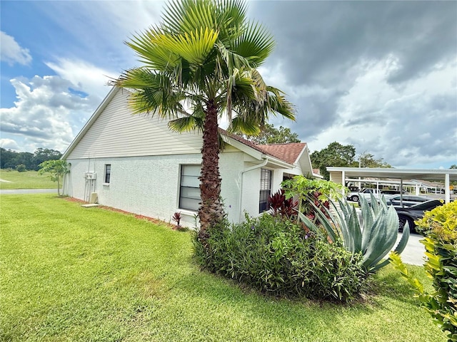 10636 Millriver Dr, New Port Richey, FL 34654 - view of side of property featuring stucco siding, a yard, and a carport