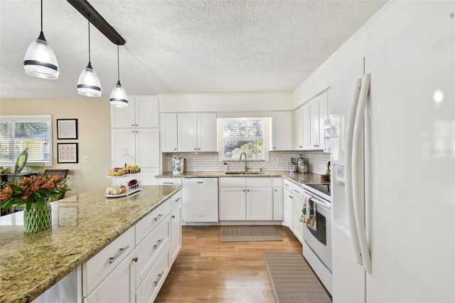616 2nd St, Indian Rocks Beach, FL 33785 - kitchen with white appliances, a textured ceiling, light wood finished floors, backsplash, and white cabinetry