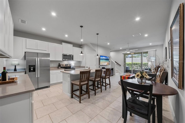 5813 Grand Sonata Ave, Lutz, FL 33558 - kitchen featuring stainless steel appliances, ceiling fan, white cabinetry, recessed lighting, and a breakfast bar