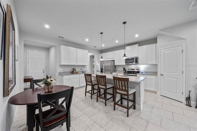 5813 Grand Sonata Ave, Lutz, FL 33558 - kitchen with stainless steel appliances, light countertops, a kitchen island with sink, recessed lighting, and a kitchen bar