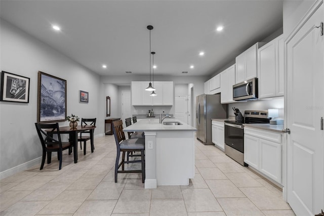 5813 Grand Sonata Ave, Lutz, FL 33558 - kitchen featuring appliances with stainless steel finishes, a kitchen breakfast bar, an island with sink, white cabinets, and recessed lighting