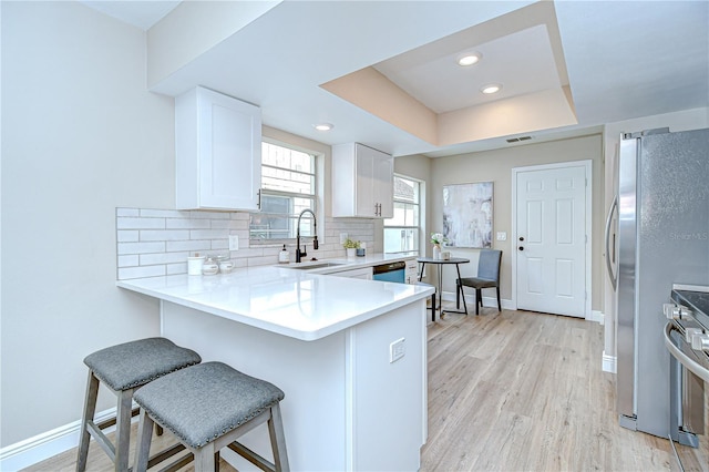 6720 Gilda Dr, Tampa, FL 33625 - kitchen featuring range, a kitchen bar, tasteful backsplash, white cabinets, and light wood-style flooring