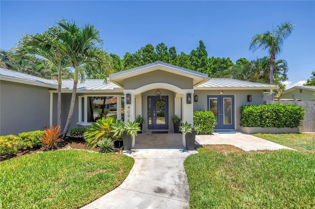 4096 38th St S, Saint Petersburg, FL 33711 - view of front of property featuring french doors, a standing seam roof, a front yard, and a metal roof