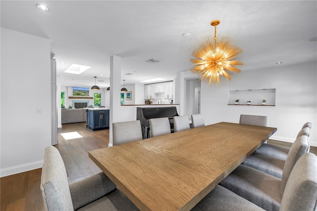 4096 38th St S, Saint Petersburg, FL 33711 - dining space with wood finished floors, a chandelier, recessed lighting, and a skylight