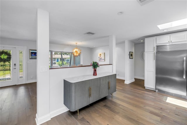 4096 38th St S, Saint Petersburg, FL 33711 - kitchen featuring built in fridge, wood finished floors, white cabinets, a skylight, and light countertops