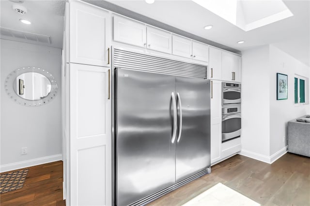4096 38th St S, Saint Petersburg, FL 33711 - kitchen with stainless steel appliances, wood finished floors, white cabinets, recessed lighting, and a skylight