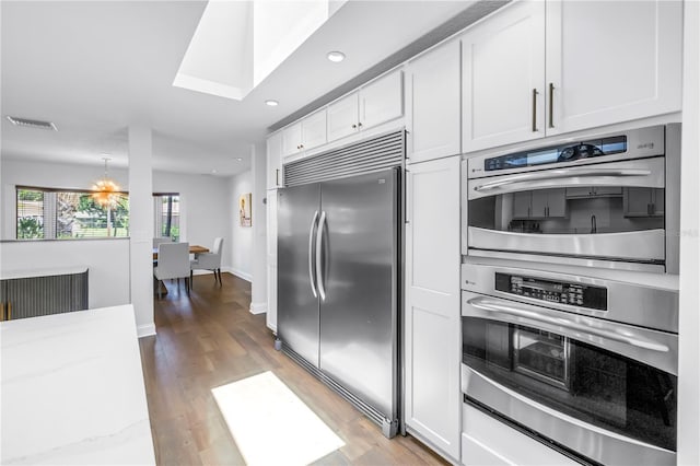 4096 38th St S, Saint Petersburg, FL 33711 - kitchen with appliances with stainless steel finishes, white cabinets, light wood-type flooring, recessed lighting, and light stone countertops