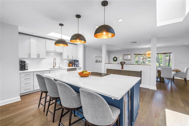 4096 38th St S, Saint Petersburg, FL 33711 - kitchen with a kitchen island, wood finished floors, white cabinetry, a kitchen breakfast bar, and recessed lighting