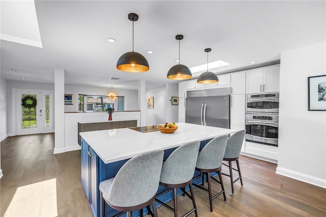 4096 38th St S, Saint Petersburg, FL 33711 - kitchen with stainless steel appliances, a kitchen island, white cabinetry, wood finished floors, and recessed lighting