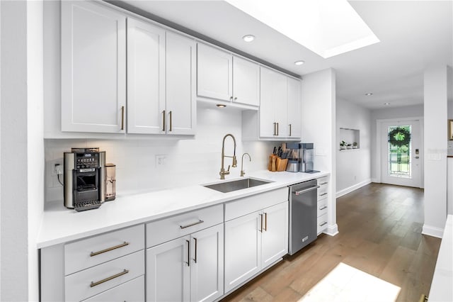 4096 38th St S, Saint Petersburg, FL 33711 - kitchen featuring stainless steel dishwasher, tasteful backsplash, light countertops, wood finished floors, and a skylight