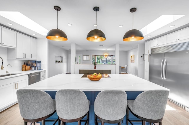 4096 38th St S, Saint Petersburg, FL 33711 - kitchen with stainless steel appliances, a center island, light wood-style flooring, white cabinets, and recessed lighting