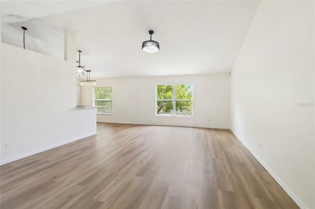 818 Cherry Laurel St, Minneola, FL 34715 - unfurnished living room featuring light wood finished floors, a chandelier, and vaulted ceiling