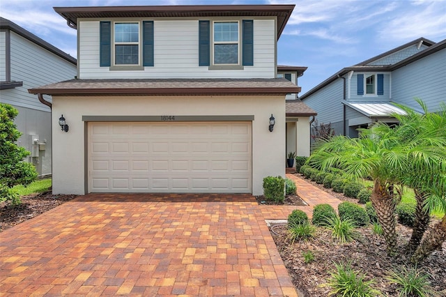 18144 Frame Bnd, Land O Lakes, FL 34638 - traditional-style house featuring stucco siding, a garage, decorative driveway, and roof with shingles