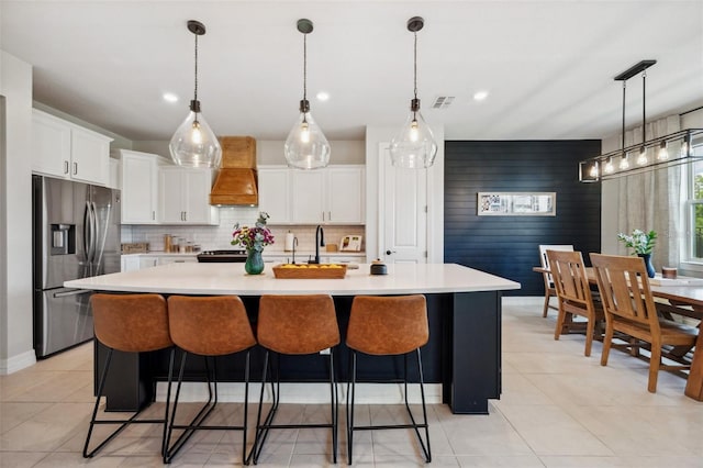 18144 Frame Bnd, Land O Lakes, FL 34638 - kitchen with stainless steel fridge with ice dispenser, premium range hood, light countertops, white cabinets, and tasteful backsplash