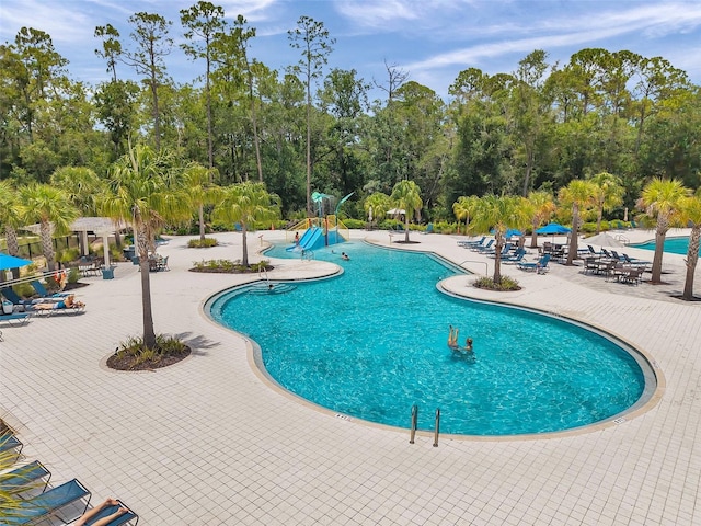 18144 Frame Bnd, Land O Lakes, FL 34638 - community pool featuring a water slide, view of scattered trees, and a patio area