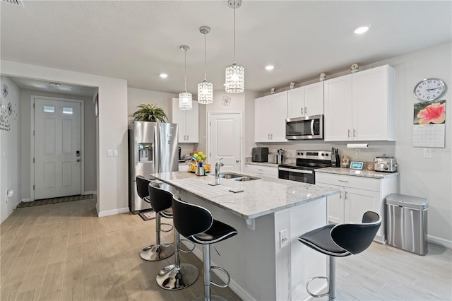 39024 Harlow Rose Dr, Zephyrhills, FL 33540 - kitchen featuring appliances with stainless steel finishes, light wood-type flooring, a kitchen bar, white cabinets, and recessed lighting